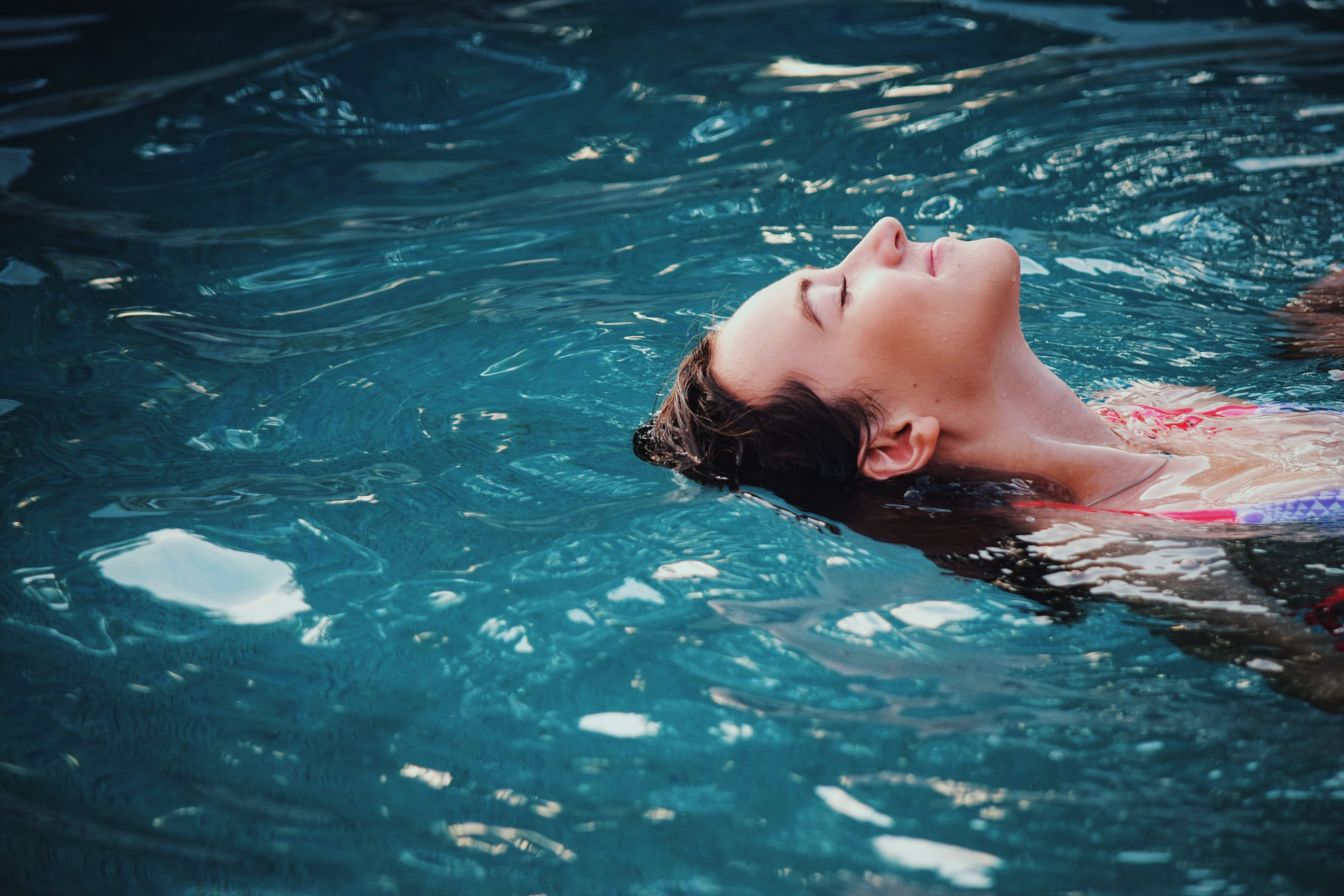 Woman relaxing by floating on her back in pool